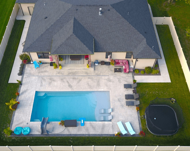 beige house with a grey roofing and a big patio around with a pool